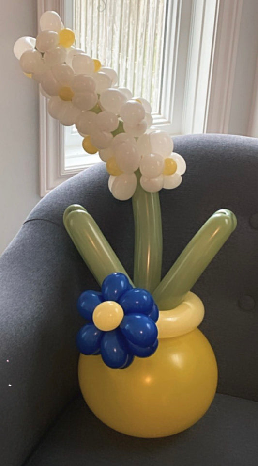 A cute yellow flower pot with adorable flowers.